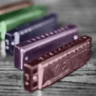 fuenf aufgestellte blues harp mundharmonikas auf einer holz tischplatte farblich hervorgehoben