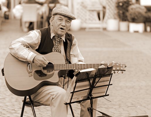 älterer Mann spielt Gitarre sitzt auf Marktplatz Noten Notenständer